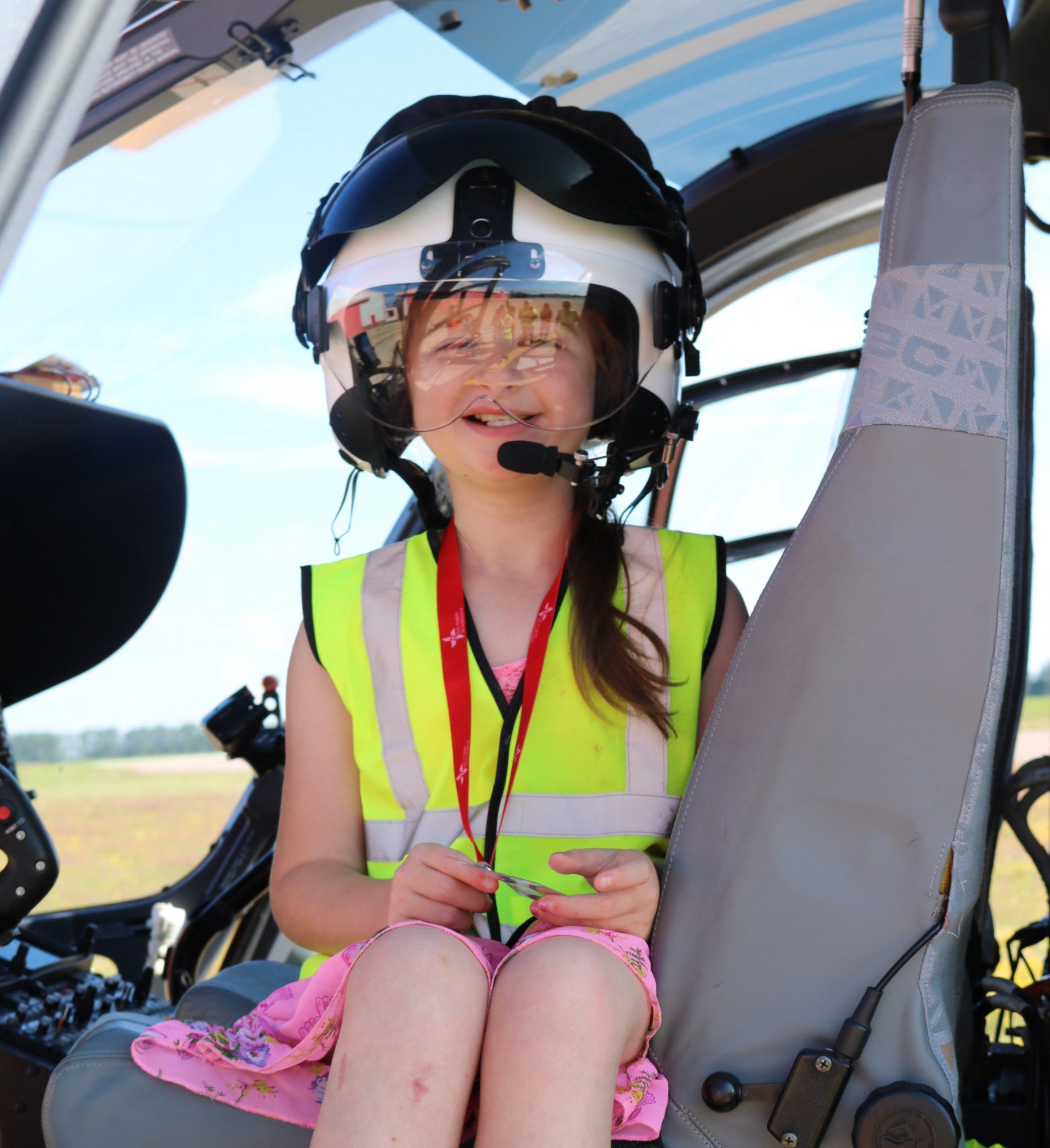 Katy Ann sitting inside the EAAA helicopter wearing a helmet. 