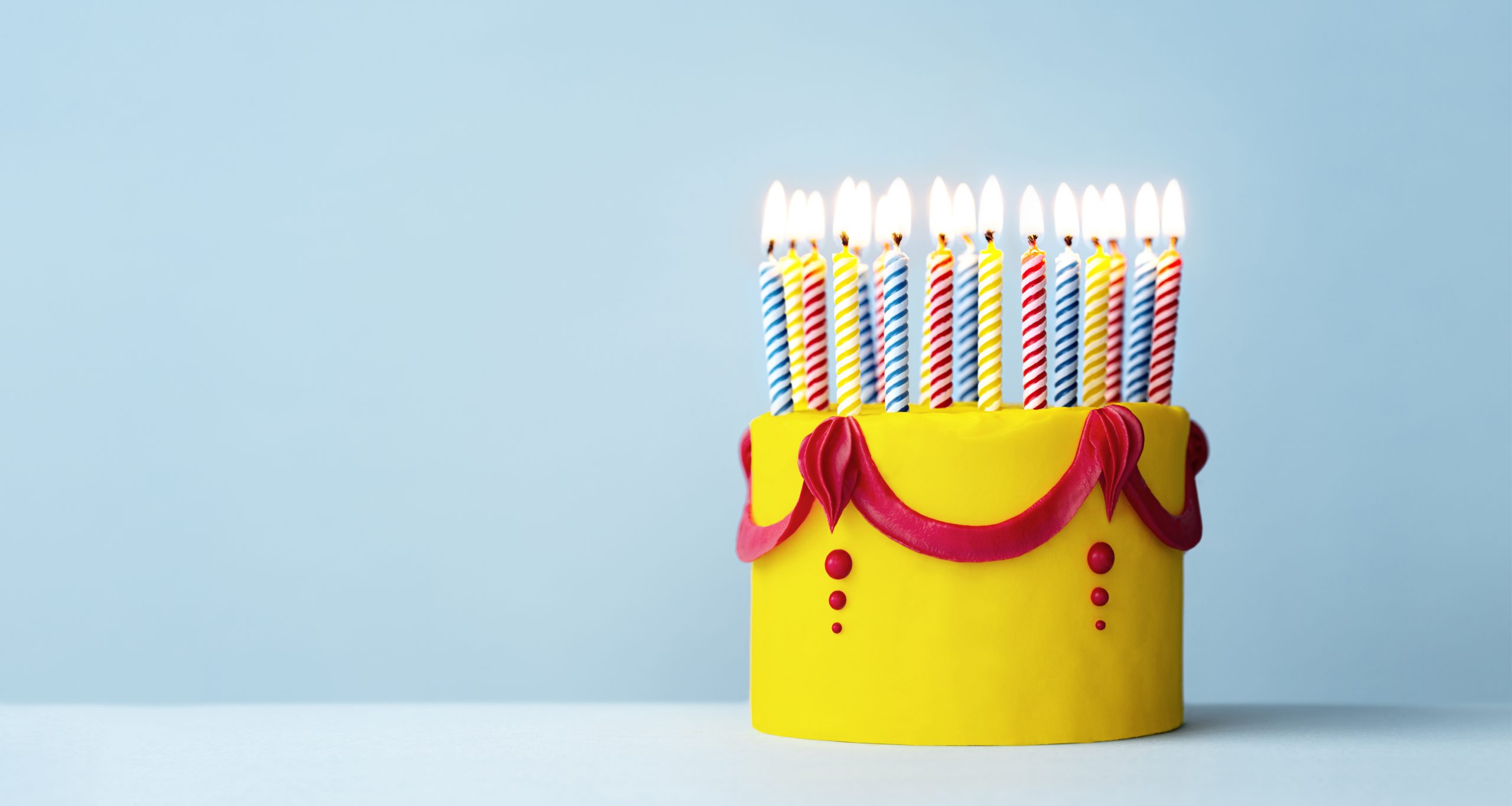 Colorful yellow birthday cake with candles