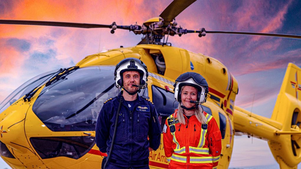 Pilot and Doctor in front of helicopter with orange sky behind