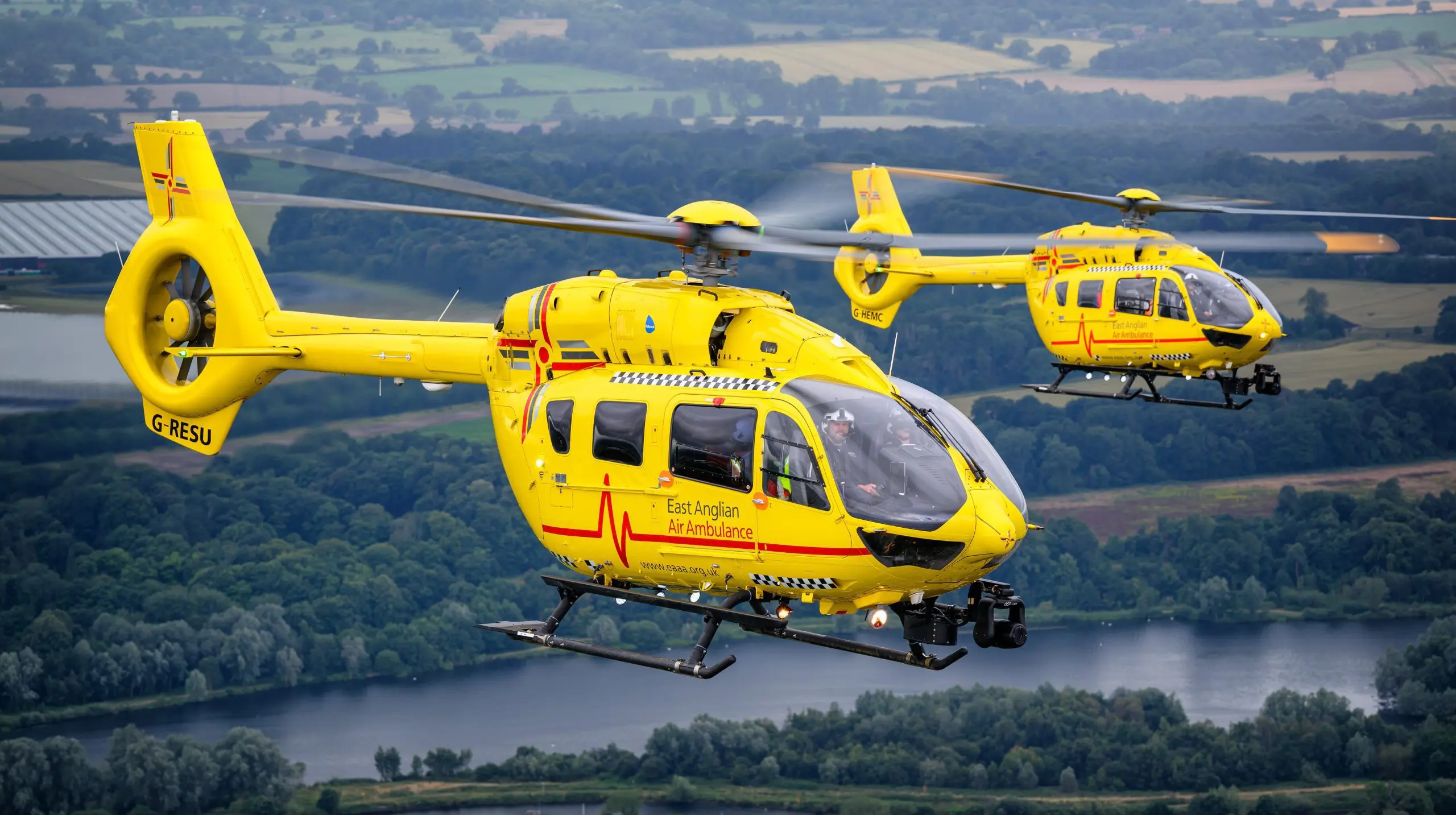 2 helicopters flying over a river in east anglia