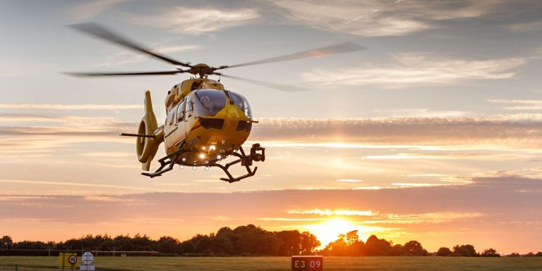 East Anglian Air Ambulance helicopter landing at sunset