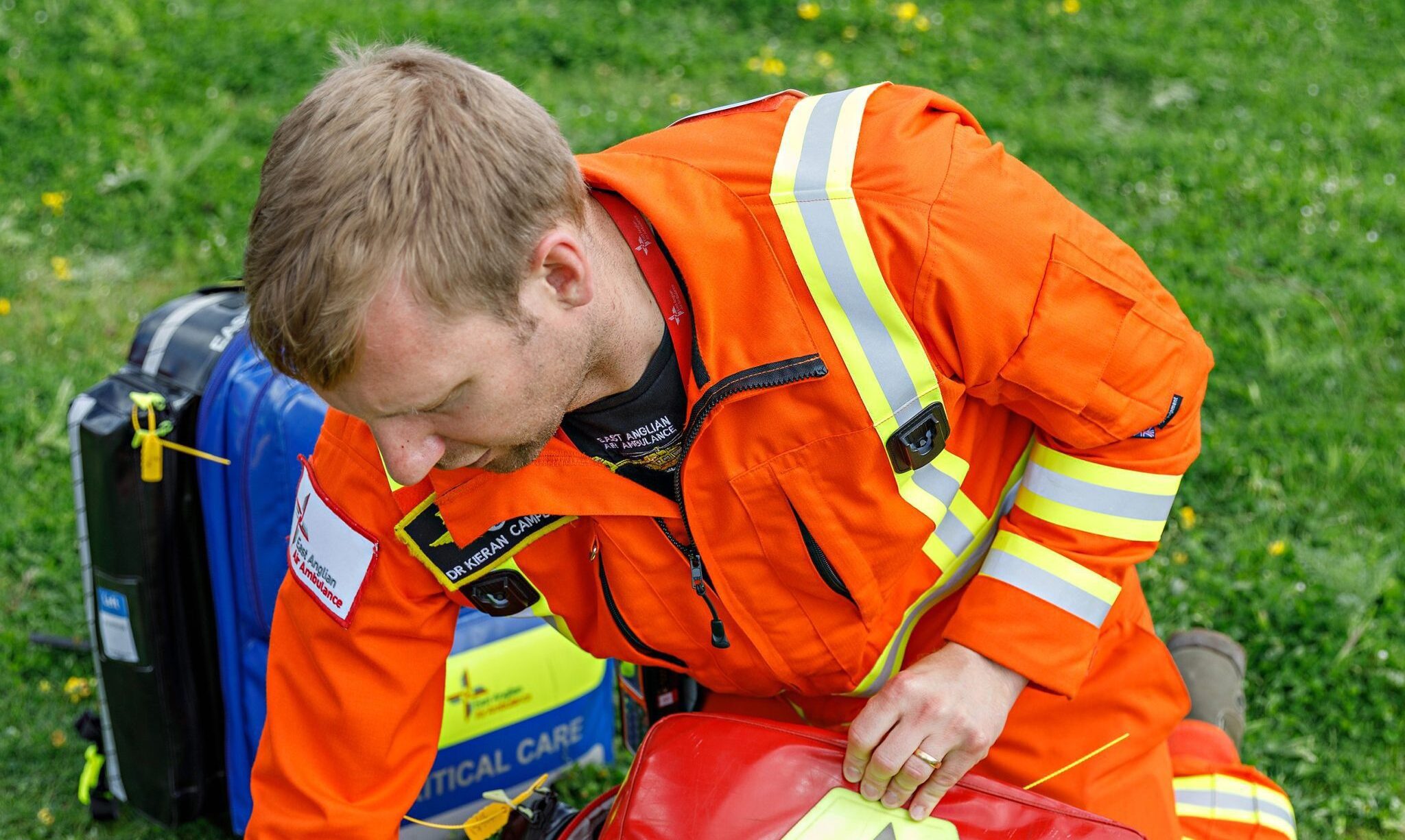 Doctor opening red kit bag on grass